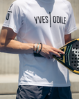Man draagt witte YVES ODILE sportkleding t-shirt tijdens padelspel met zwart gele padelracket